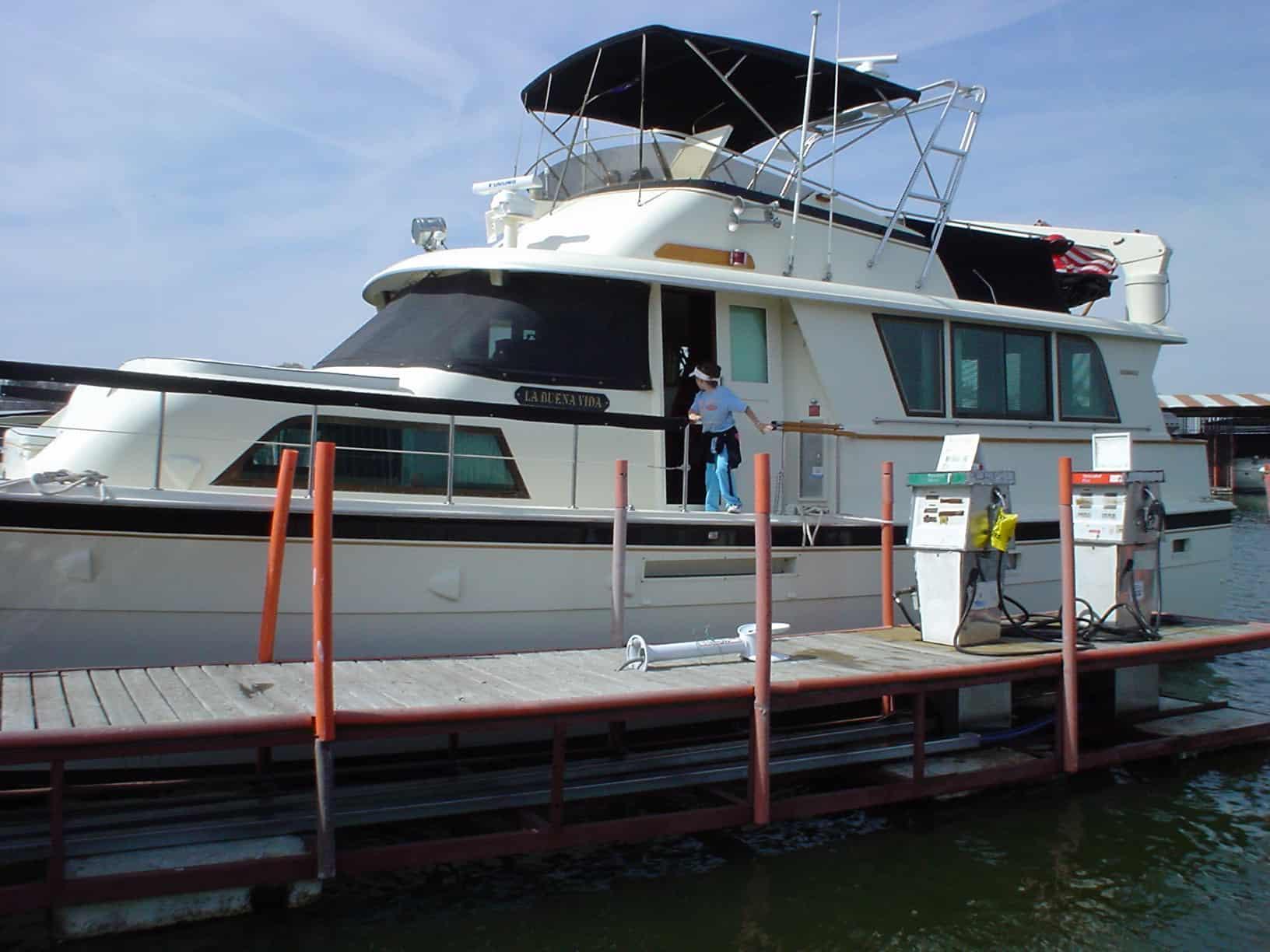 Hattaras 53 Extended Deckhouse MY yacht docked at a marina with a person standing on the swim platform and Atlantic Towers arch installed.