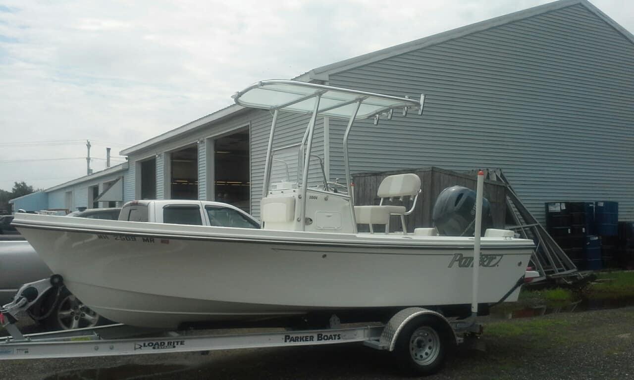 Parker boat on a trailer equipped with an Atlantic Towers T-Top, parked beside a large industrial building.