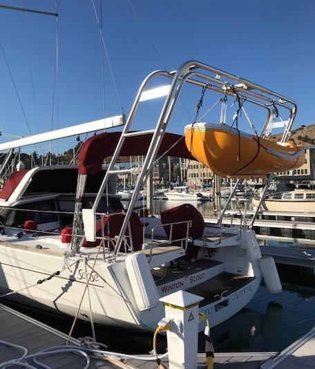 Beneteau sailboat docked with Atlantic Towers Arch supporting a suspended yellow dinghy in a marina.