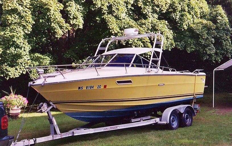 Sea Ray SR 220 boat on a trailer in grass with an installed Atlantic Towers arch and surrounding trees.