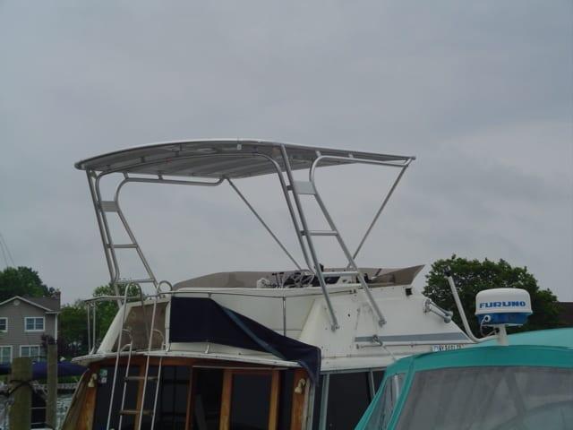 Bayliner 3888 MY boat with installed Atlantic Towers Top stainless steel frame and canvas cover docked near waterfront homes.