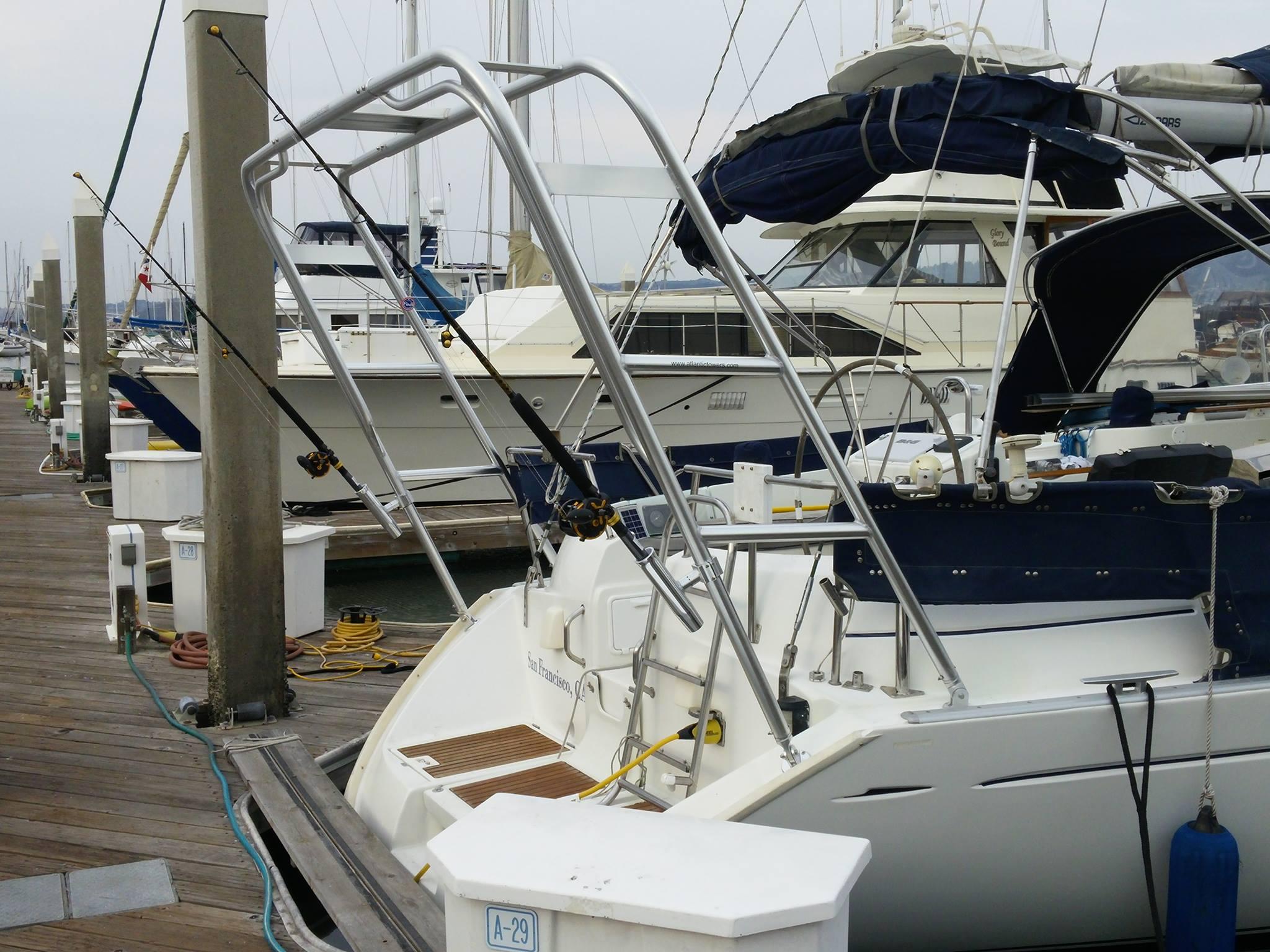 Beneteau boat docked with an installed Atlantic Towers Arch holding fishing rods on the stern near a marina pier.