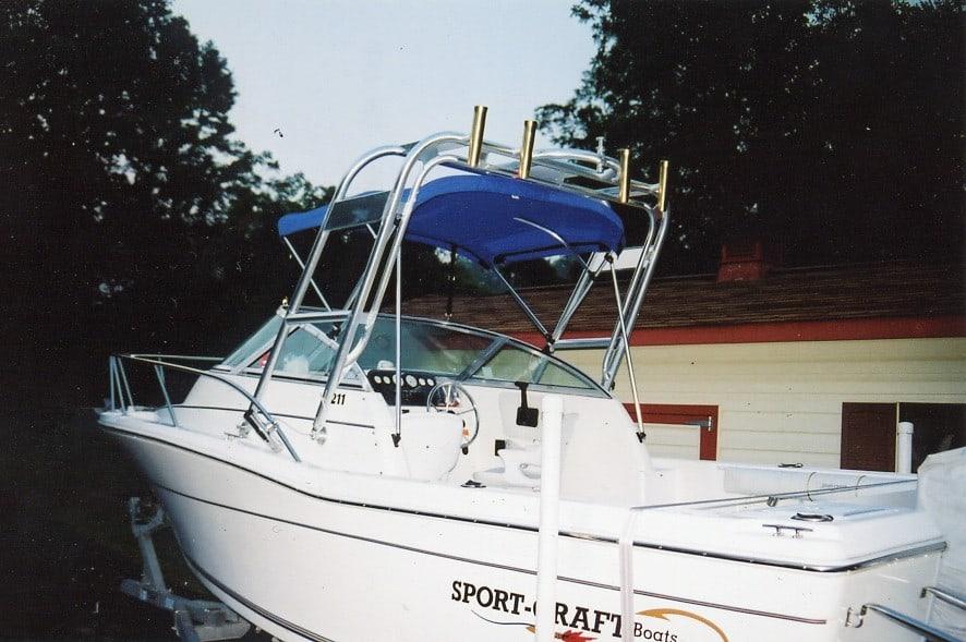 Sportcraft 211 W/A boat equipped with Atlantic Towers Arch with blue canopy and rod holders docked near a building.