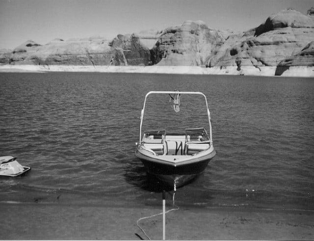 Four Winns 210 Horizon boat with Atlantic Towers Air Tower anchored near a rocky shoreline in calm water.
