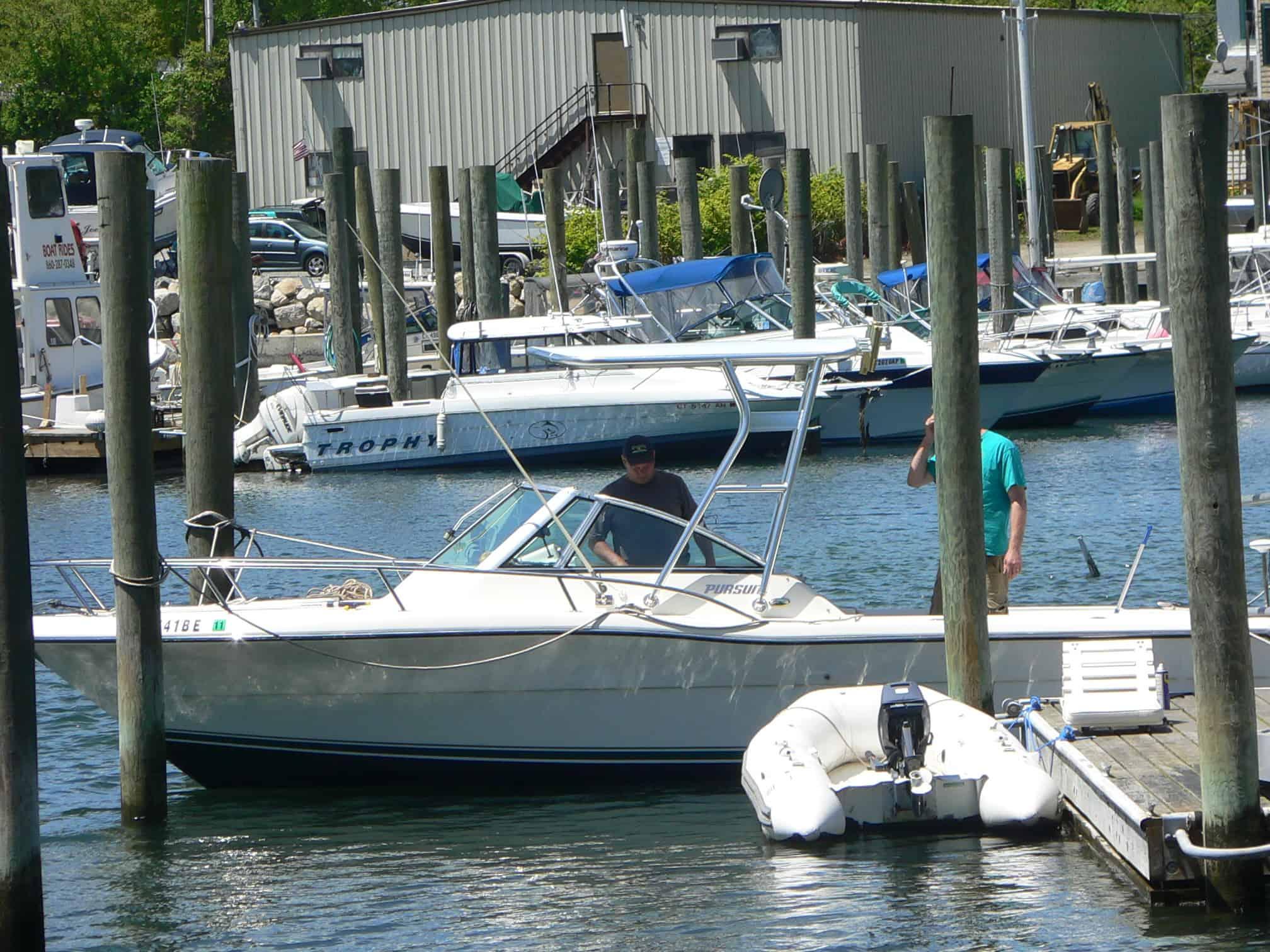 Pursuit 2460 Denali boat docked with Atlantic Towers Top installed, with people visible on the boat and dock nearby.