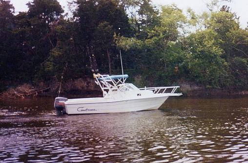 Pro Sport 2200 W/A boat with Atlantic Towers Arch installed, floating on calm water near a tree-lined shore.