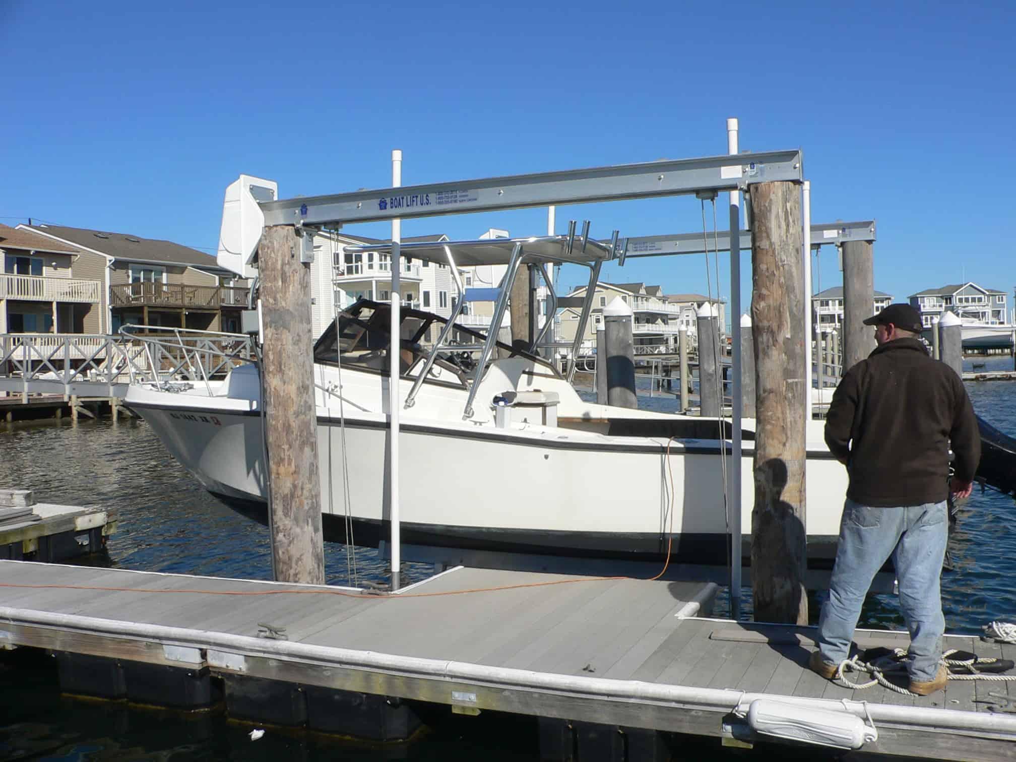 Mako 258 Cuddy boat with Atlantic Towers Top installed, hanging on a lift at a marina dock with a man nearby.