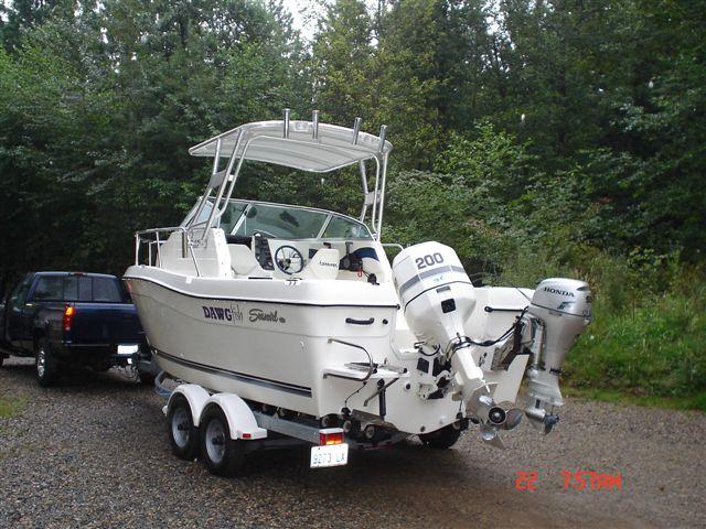 Seaswirl 2100 Walkaround boat with dual outboard motors and installed Atlantic Towers Top on trailer near wooded area
