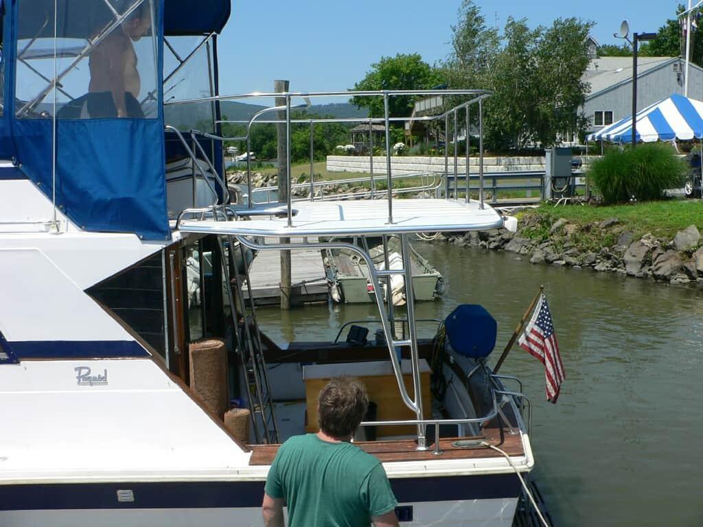Pequod 34 Sedan boat with Atlantic Towers Cockpit Sun Shade installed on the rear deck near a dock with a man in green nearby.