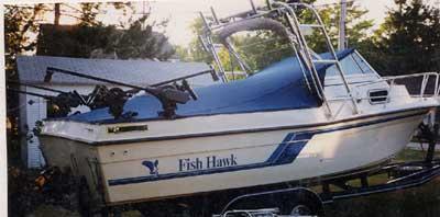 Atlantic Towers Arch installed on a Celebrity 2300 Fish Hawk boat on a trailer outdoors near trees and a shed.