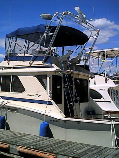 Atlantic Towers Arch installed on a Chris Craft boat with a blue canvas top, docked at a marina.