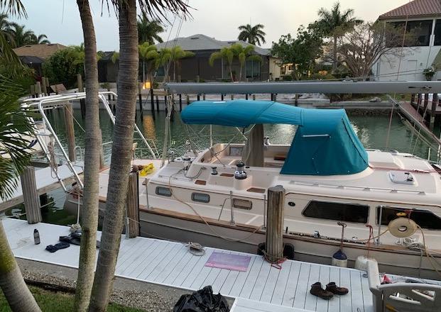 Sailboat docked at a canal home with an installed Atlantic Towers Arch supporting rigging and a blue canopy.