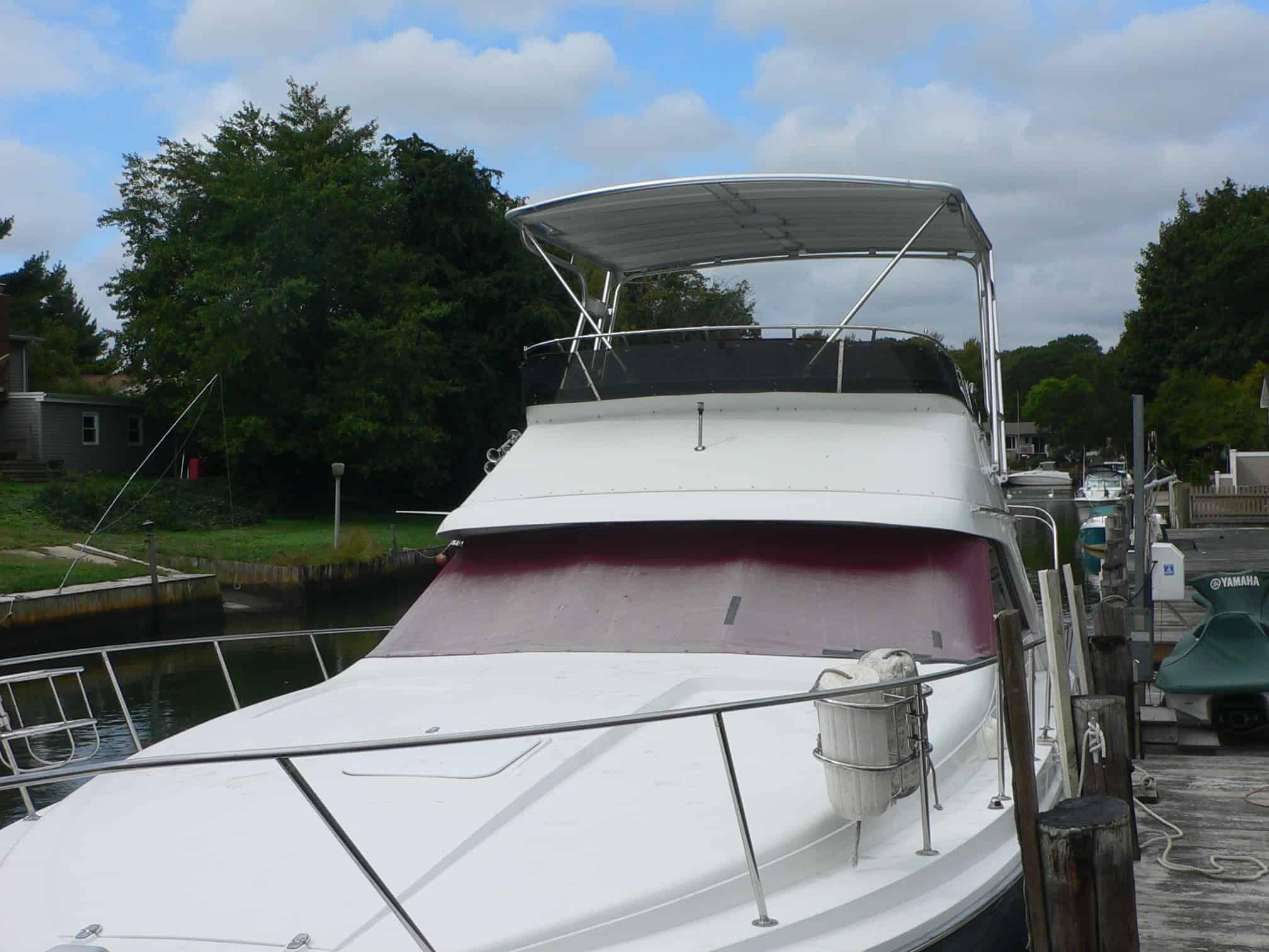 Atlantic Towers Top installed on a Trojan 11 Meter Sedan boat, moored at a dock with nearby trees and water.
