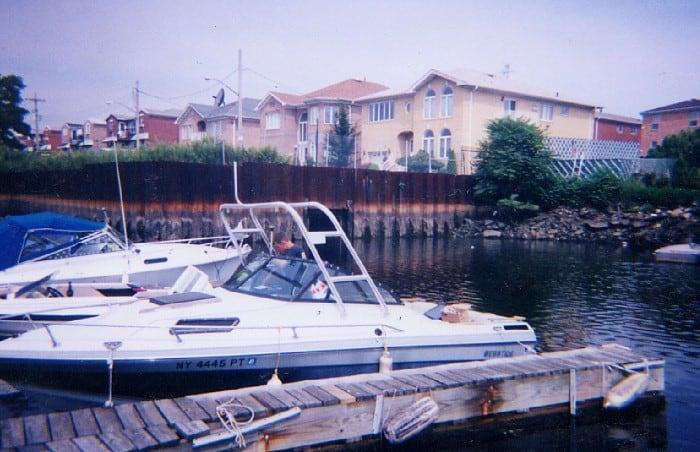 Ebbtide boat docked near wooden pier with Atlantic Towers Arch installed, residential buildings in background.