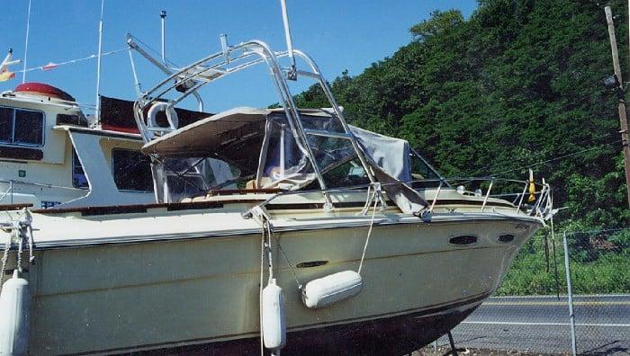 Sea Ray 255 Amberjack boat equipped with Atlantic Towers Arch docked near a fenced area with trees in the background.