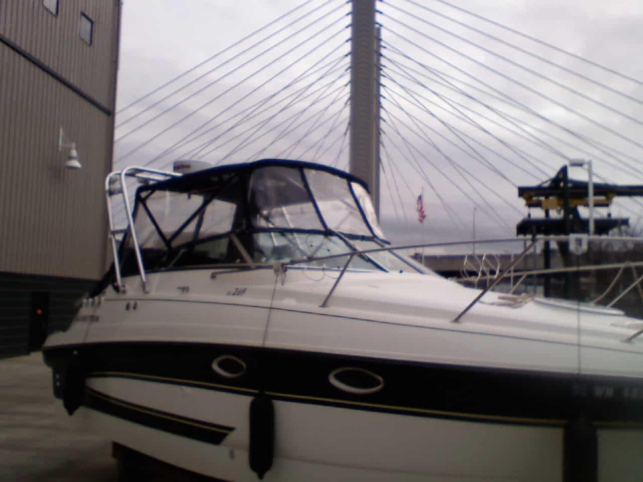 White and black Glastron GS269 boat docked near a building with an installed Atlantic Towers Arch on the cabin cover.