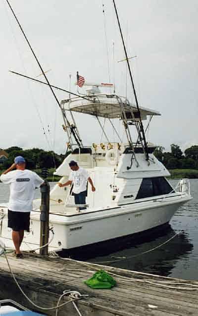 Atlantic Towers Top installed on a Phoenix 29 SFX Conv. boat docked with two men onboard near a wooden pier