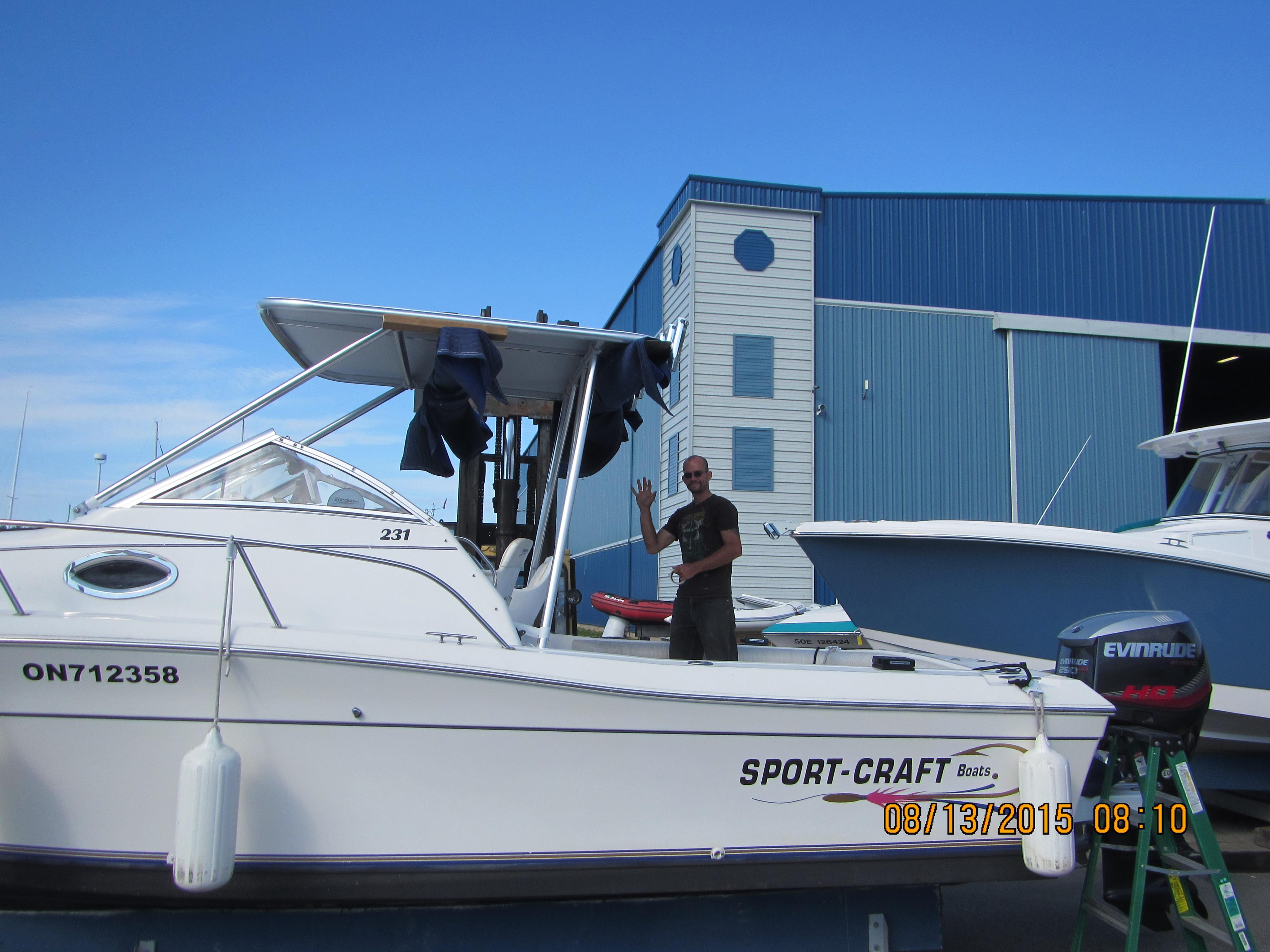 Sportcraft boat with Atlantic Towers Top installed, showing a man waving while docked by a large blue building.