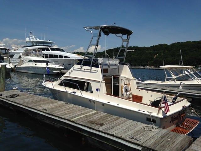 Pacemaker boat equipped with Atlantic Towers Top installed, docked at marina with surrounding boats and hills.