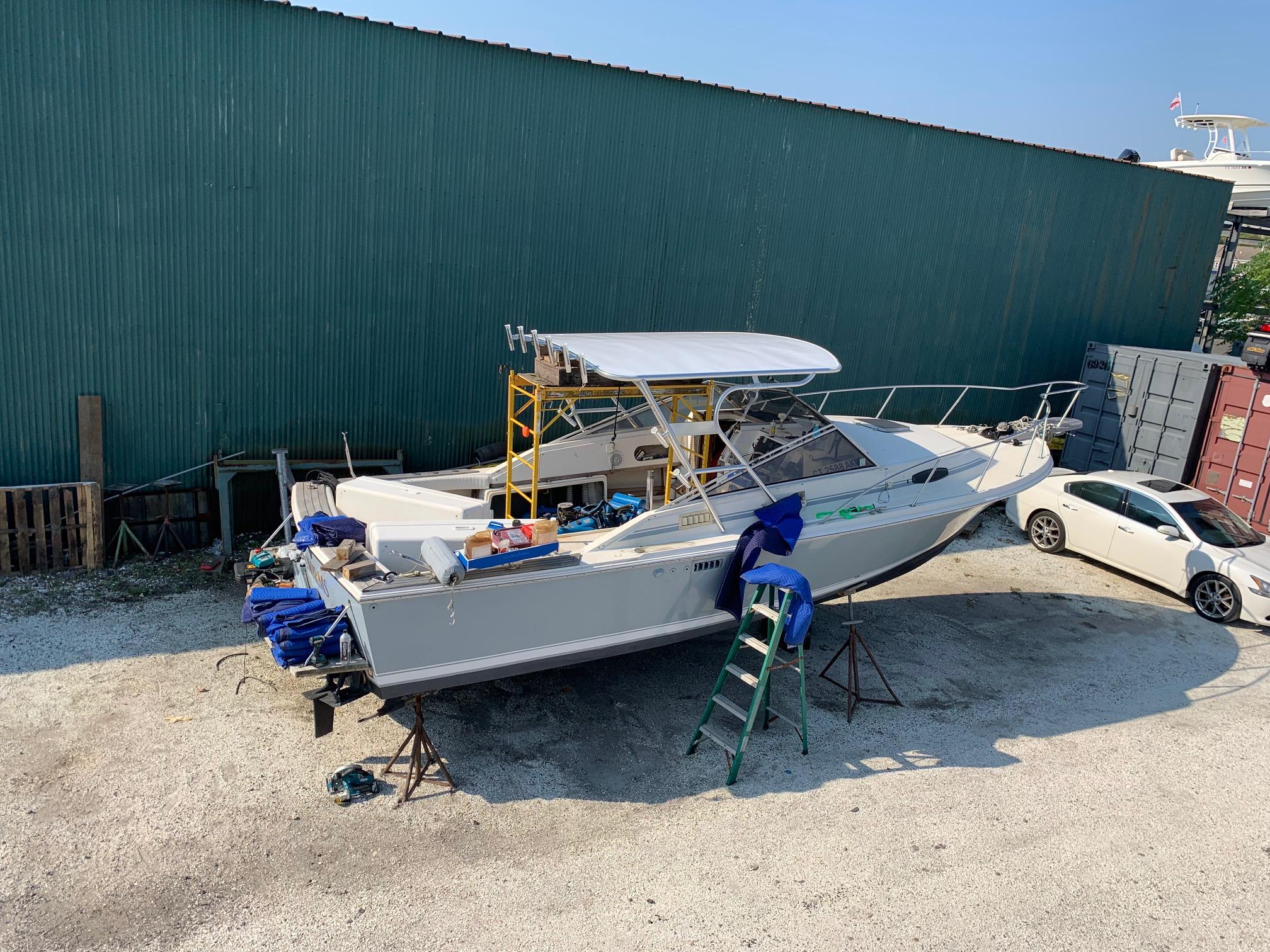 Atlantic Towers Top installed on a Blackfin boat, with tools and blue tarps arranged on a trailer in a lot.