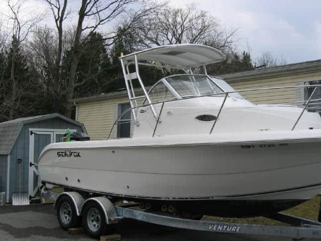 Sea Fox 230 walk around boat on trailer equipped with Atlantic Towers Top canopy in a driveway near a shed.