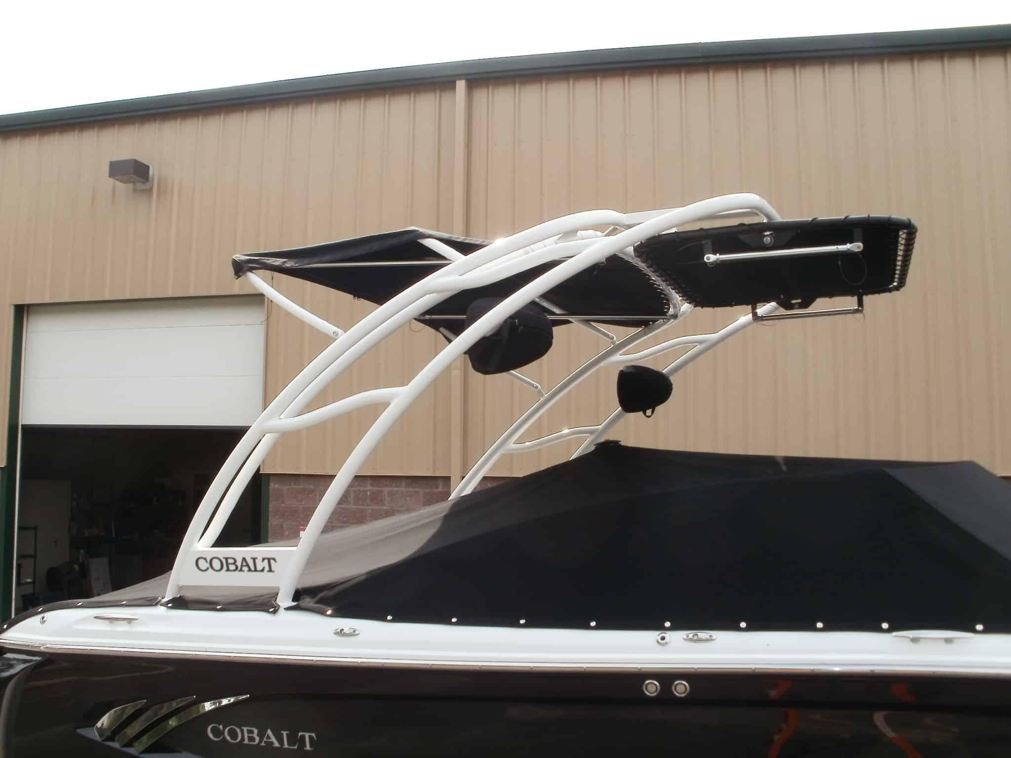 Atlantic Towers arch installed on a black and white Cobalt A25 boat with a black cover, shown in front of a beige building.
