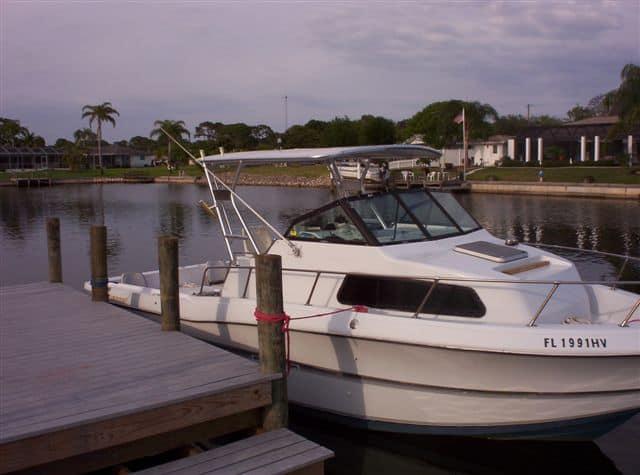 Renken 2688 boat docked with Atlantic Towers Top installed, near waterfront houses and palm trees at dusk.