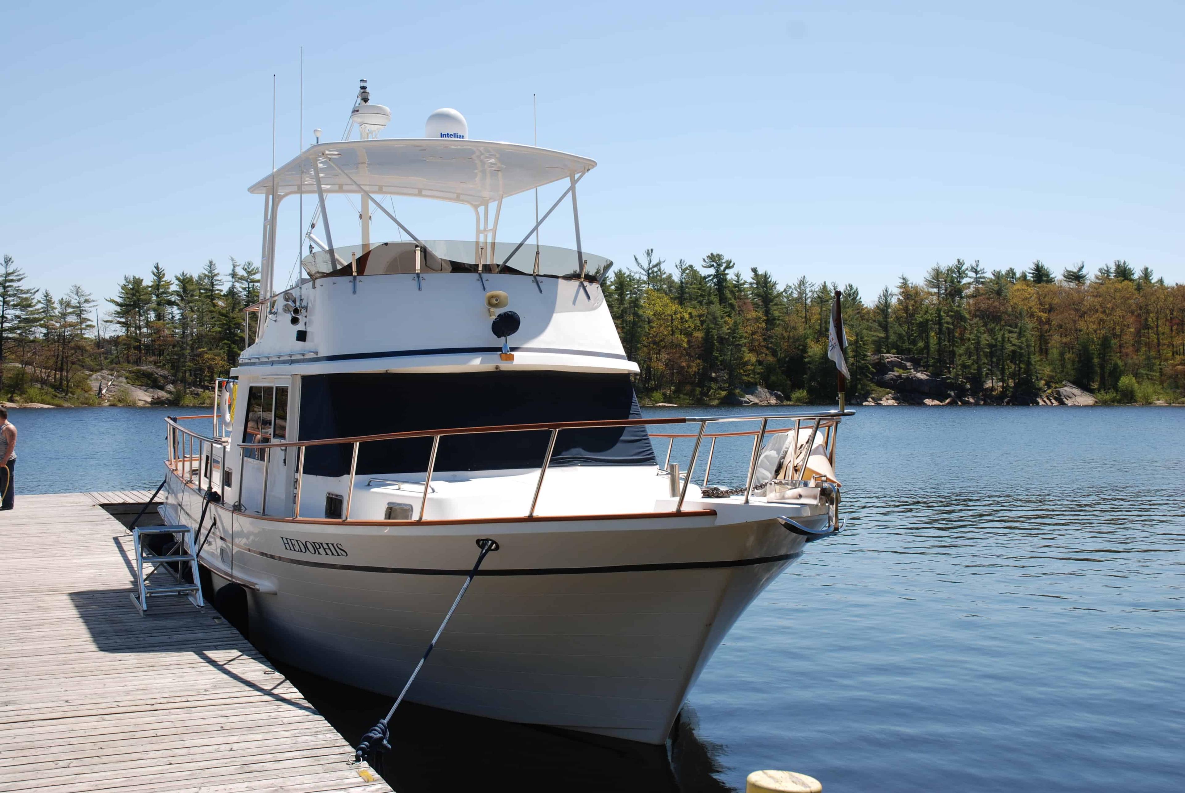 Atlantic Towers Top installed on the flybridge of a white Monk 42 Trawler docked beside a wooden pier on a clear day