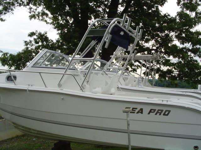 Sea Pro 206 W/A boat equipped with Atlantic Towers Arch parked on land with trees in the background.