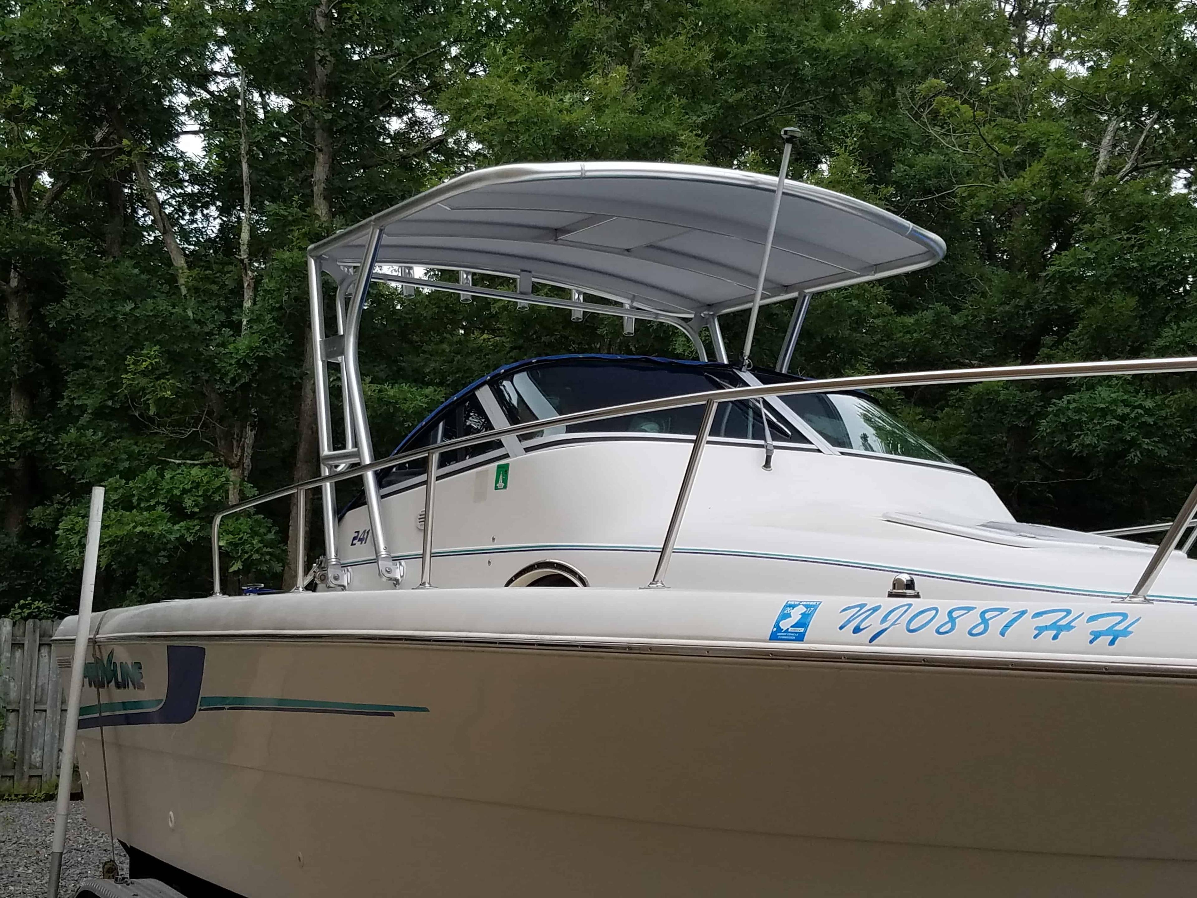 Pro Line boat with installed Atlantic Towers Top aluminum frame and canvas hardtop roof, parked near trees.