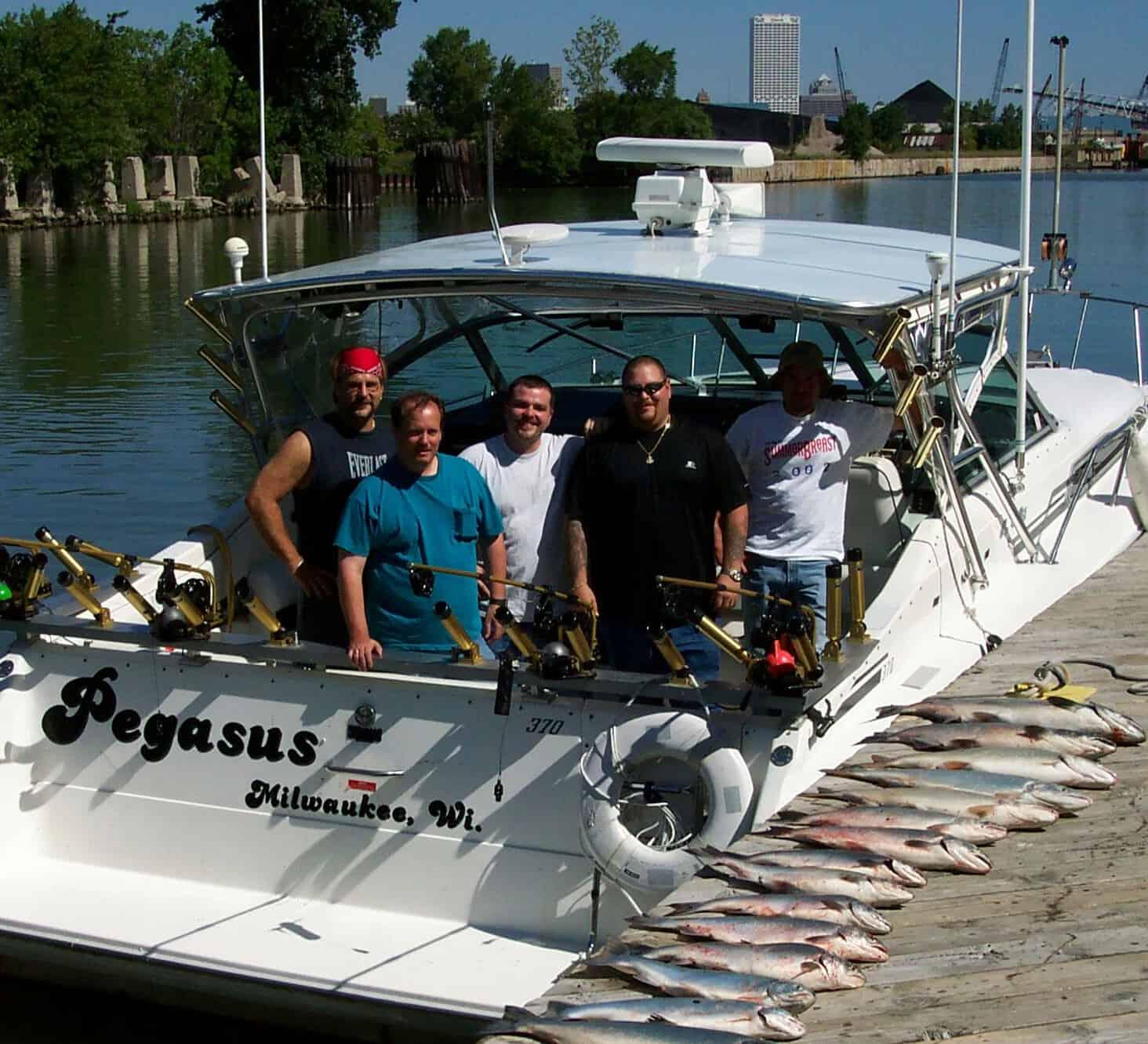 Five men posing on a Sea Ray 350/370 Sundancer with Atlantic Towers Top, docked with a catch of fish lined up on the pier