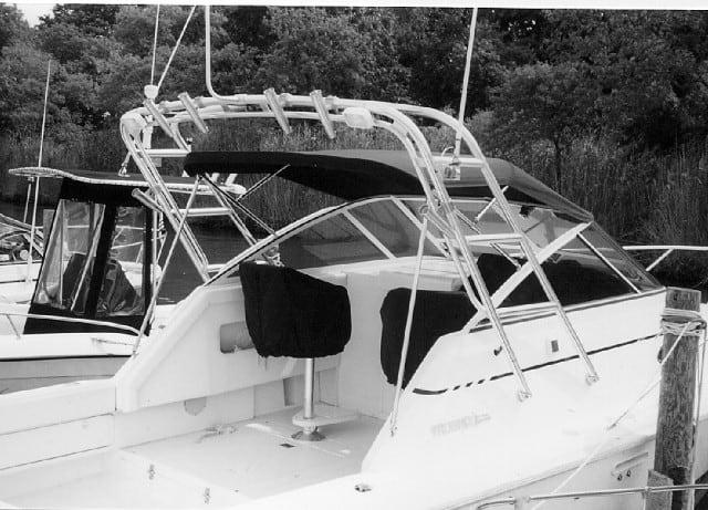 Side view of a Phoenix 27 Tournament II boat with an installed Atlantic Towers Arch and black seat covers docked near trees.
