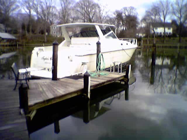 Tiara 40 Express boat docked with Atlantic Towers Top installed, surrounded by calm water and trees in the background.