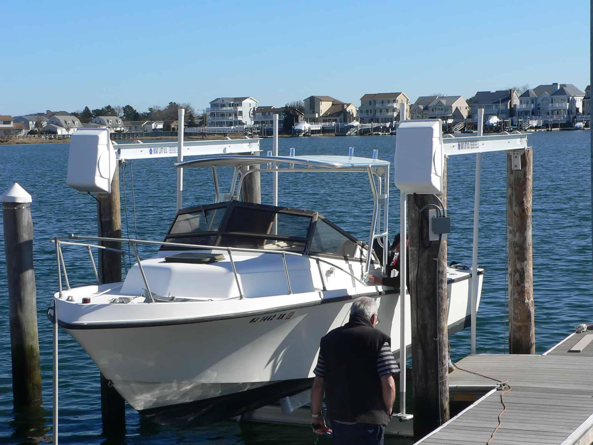 Atlantic Towers Top installed on a white Mako 258 Cuddy boat docked near a wooden pier with a man standing nearby.