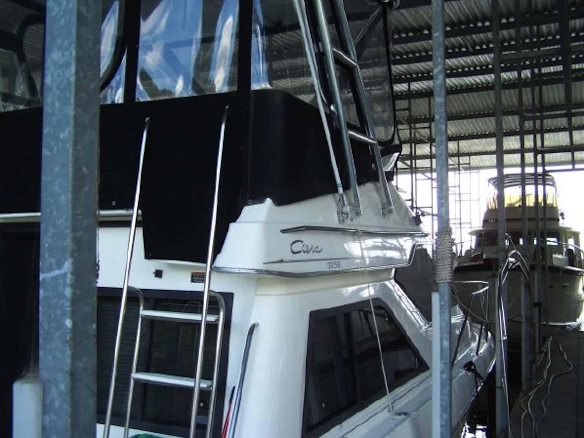 Atlantic Towers Top installed on a white Bayliner 3258 Command Bridge boat with a metal ladder and black enclosure in a covered dock.