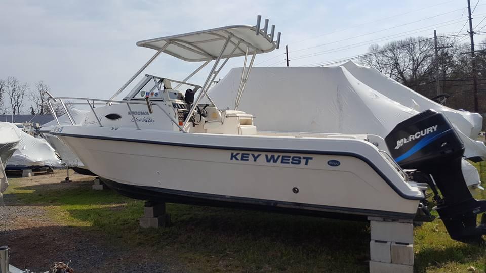 Key West boat with Atlantic Towers Top installed, equipped with outboard Mercury motor, on dry storage blocks outdoors.