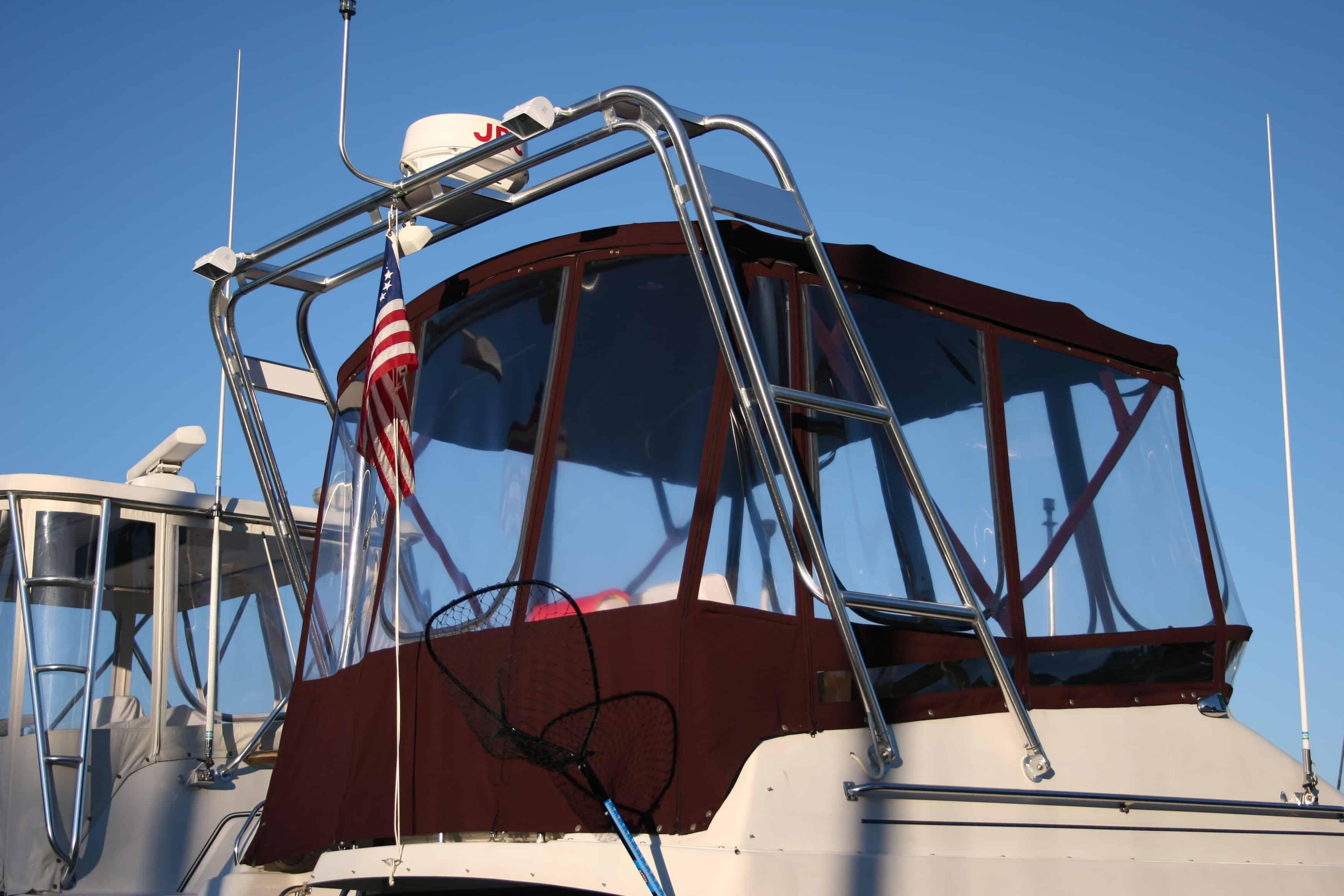 Atlantic Towers arch installed on the upper deck of a Silverton 34 Convertible boat with clear enclosure and American flag.