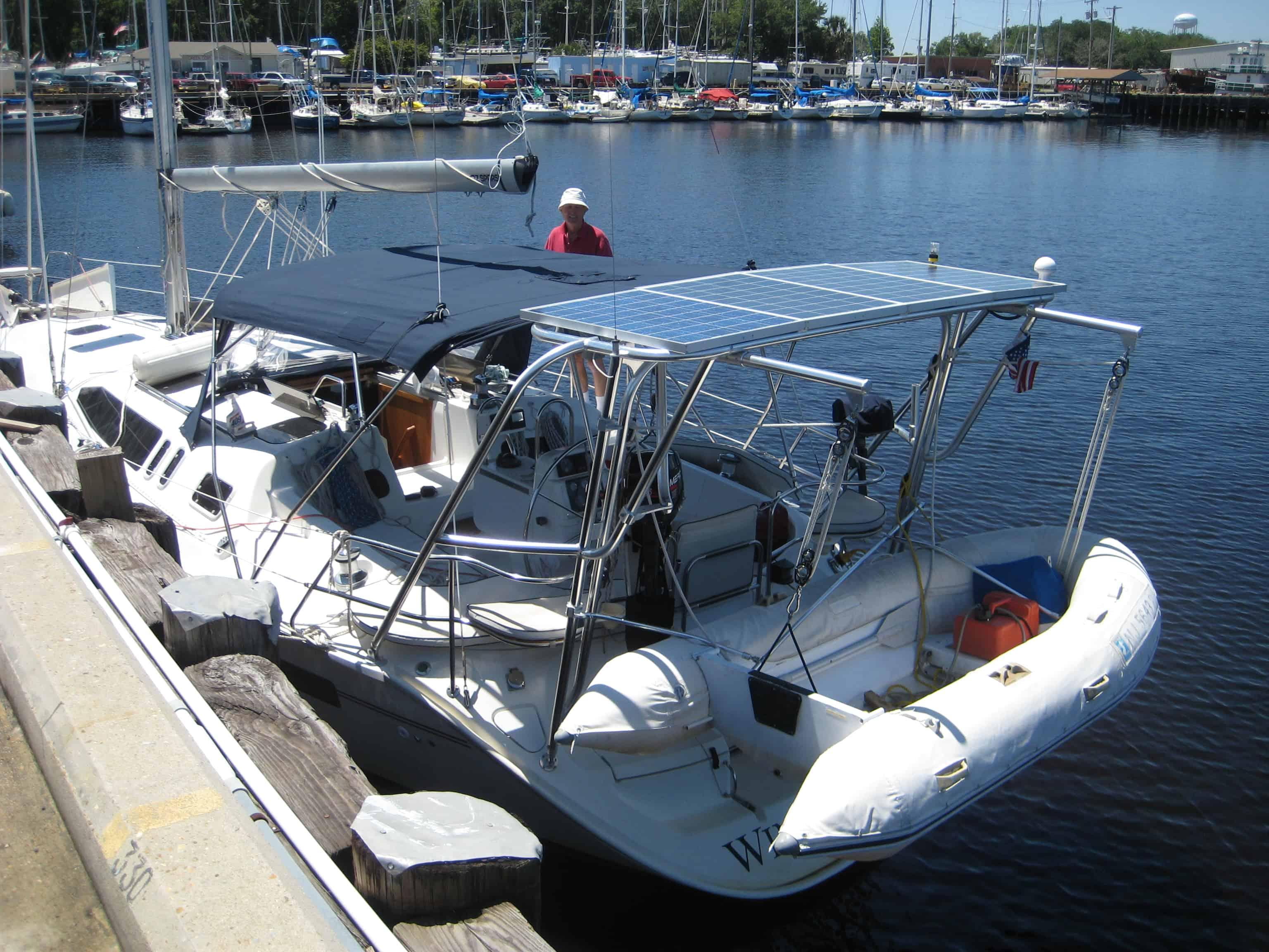 Hunter sailboat docked with Atlantic Towers arch featuring solar panels and a small inflatable dinghy attached at the stern.
