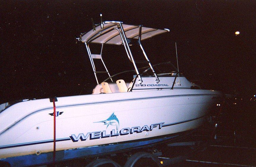 Wellcraft 218 Coastal boat with installed Atlantic Towers Top frame and canopy on trailer at night.