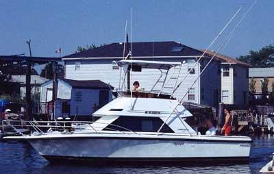 Phoenix 29 SFX Convertible boat on water with Atlantic Towers Top installed, people visible on deck near waterfront buildings