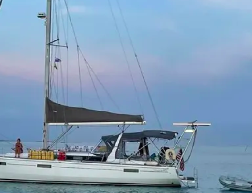 Beneteau sailboat on calm water with a black Atlantic Towers Arch installed at the stern and a small dinghy nearby.