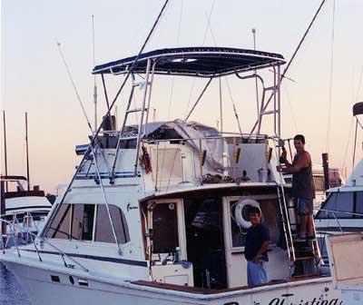 Atlantic Towers Top installed on an Egg Harbor 33 Convertible boat with two men on the deck at sunset.