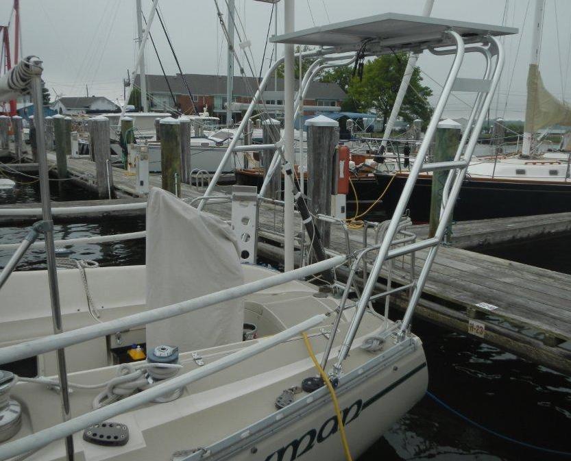 Atlantic Towers arch installed on an O'Day sailboat docked at a marina with other boats in the background.