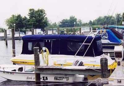 Donzi Deck Boat docked with Atlantic Towers Arch and canvas cover, surrounded by other boats at marina.