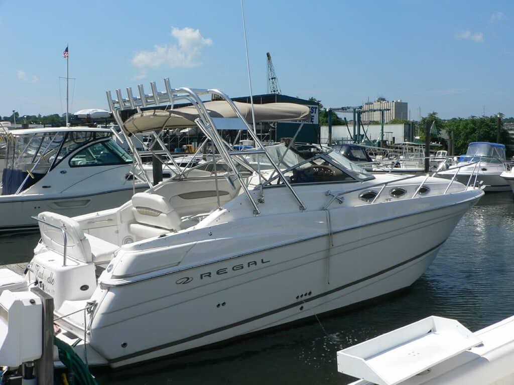 White Regal 2660/2765 Commodore boat docked with installed Atlantic Towers Arch and tan bimini top on a sunny day