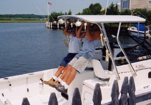 Two men exercising on the Atlantic Towers Top of a Bayliner 2509 Trophy Walkaround boat by the water.