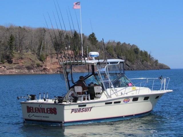 Tiara 2700 Pursuit boat with Atlantic Towers Top installed, fishing rods, and an American flag on calm water near forested shore.