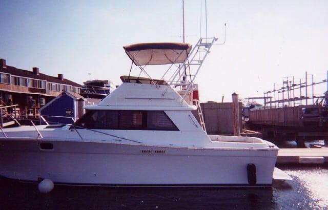 Side view of a Silverton 34 Convertible boat docked near a marina with Atlantic Towers Arch installed on top.