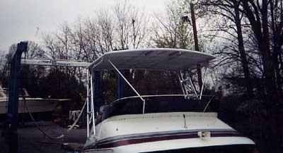 Atlantic Towers Top installed on a Trojan 10.8 Meter Sedan, showing the boat's front and canopy against a leafy background.