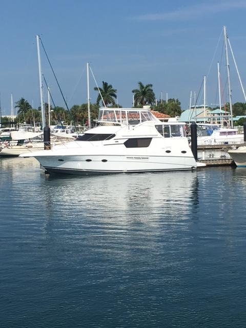 White Silverton boat docked in a marina with Atlantic Towers Top installed, palm trees and clear sky in background.